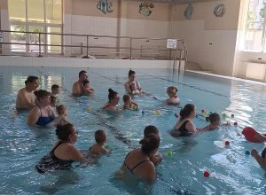 A képen a színes labdák összegyűjtése látható, a gyermekek a medencében a nyúlás, fogás, elengedés gyakorlása mellett még a színeket is tanulják.