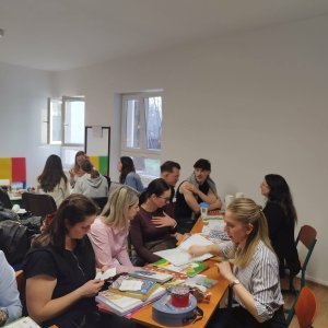 A képen a résztvevők kisebb csoportokban, asztalokat körbeülve ismerkednek a logopédusok eszközeivel.