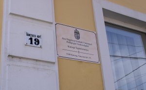 A képen az új épületre kihelyezett tábla és a 19-es házszám látható.