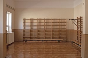 A képen a gyógytestnevelés ellátására szolgáló terem látható a falra felszerelt bordásfalakkal és az előttük lévő tornapadokkal.