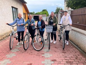 A képen a Kunhegyesi Tagintézmény munkatársai láthatóak a csapatépítő kerékpározás előtt egy kocsibejárón, kerékpárjaik mellett.