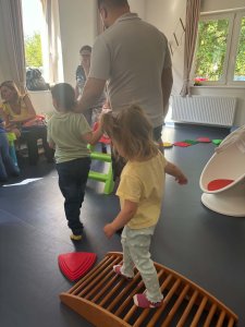 A képen a gyerekek a mozgásfejlesztő akadálypályát használják, ki szülői segítséggel ki már ügyesen egyedül.