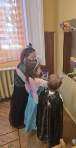 A képen a gyerekek a tükör előtt állva bemutatják a jelmezeiket.