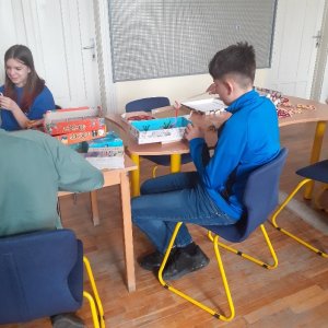 A képen a tanulók az asztalaiknál ülve végzik a foglalkozáson kiadott feladatokat.