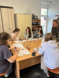 A képen a tanulók egy asztalt körbe ülve építik a 3D alkotásaikat egy pedagógus jelenlétében.