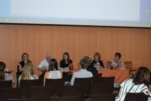 A képen a szimpózium díszvendégei és szervezői láthatóak a főasztalnál ülve.