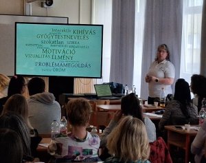 A képen a rendezvényen előadója és a résztvevők láthatóak egy tanteremben, az előadás közben.