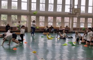 A kép egy gyógytestnevelési foglalkozás pillanatait örökíti meg, amint a gyerekek végzik a gyakorlatokat a tornateremben.