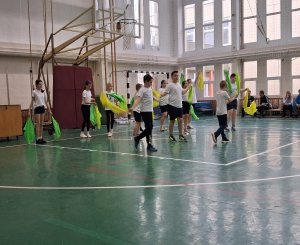 A kép egy gyógytestnevelési foglalkozás pillanatait örökíti meg, amint a gyerekek végzik a gyakorlatokat a tornateremben.