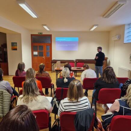 A képen Kovács Lőrinc bemutatja PPT-jét, miközben a hallgatóság figyel.