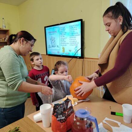 A képen pedagógusaink segítségével a gyerekek halloweeni töklámpást készítenek, éppen a magozás fázisában.