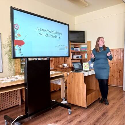 A képen a fórum előadója látható az interaktív tábla mellett állva tartja az előadását.