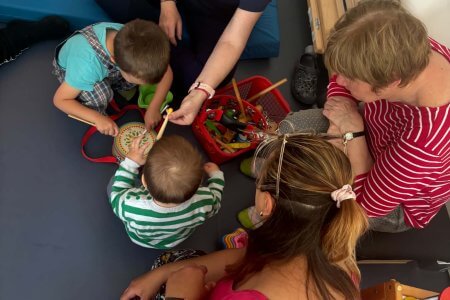 A képen az apróságok ismerkednek a hangszerekkel, énekekkel, mondókákkal. A zene a közös nyelv minden korosztály számára.