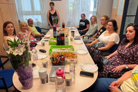 A képen a Jászberényi Tagintézmény munkatársai láthatóak a tanári szobában a tárgyaló asztalt körbeülve miközben figyelmesen hallgatják a csapatépítő napjának programmenetét.