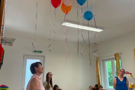A képen a családi délelőtt egy izgalmas pillanatát örökíti meg, a színes héliummal töltött lufik felengedése a tanterem mennyezetére hatalmas sikert aratott a gyerkőcök körébe.